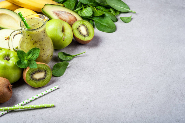 Здоровый детоксикационный коктейль с киви, авокадо, бананом, яблоком и шпинатом. Зеленый смузи на сером фоне. Концепция здорового питания и питания
 - Фото, изображение