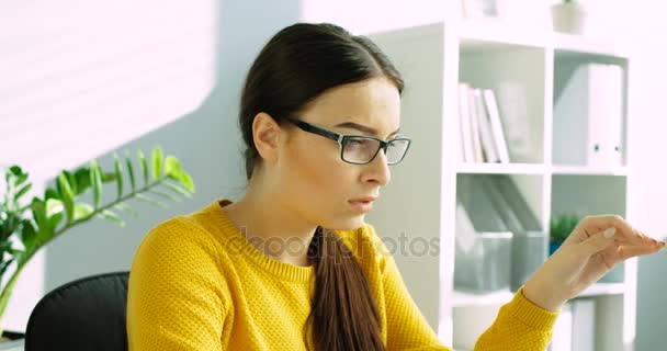 Unavený mladá žena jí brýle a masírovat oči. Žena v kanceláři unavené oči, bolest hlavy. Detailní záběr - Záběry, video
