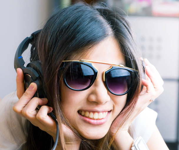 Aasian tyttö silmälasit on kuunnella musiikkia kuulokkeilla
 - Valokuva, kuva