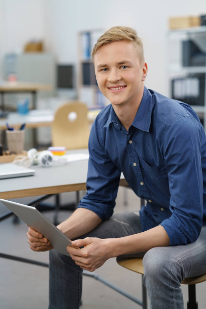 Relaxed young man using a tablet at the office - Photo, image