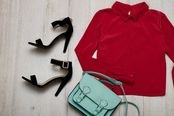 Bordeaux-Bluse, schwarze Schuhe, Handtasche. modisches Konzept. hölzerner Hintergrund - Foto, Bild