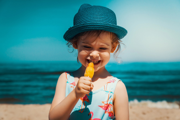 Little and cute girl eating ice cream on the beach - Foto, afbeelding