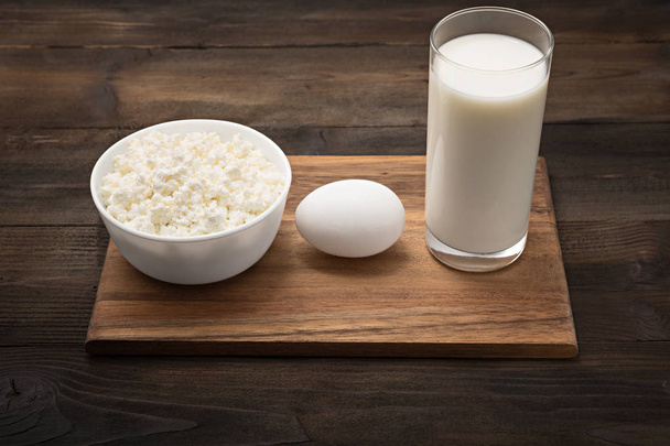 Dairy products on wooden table. Cottage cheese, milk, egg. Top view with copy  - Photo, Image