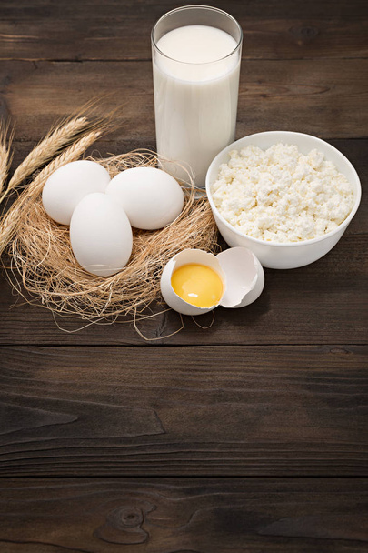 Productos lácteos sobre mesa de madera. Queso cottage, leche, huevo y yema de huevo. Vista superior con copia
  - Foto, imagen