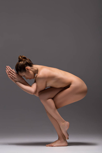 Serious naked girl locating in eagle pose - Foto, afbeelding
