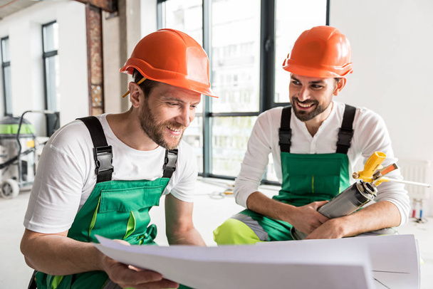 Hilarious smiling constructors keeping plan - Фото, изображение