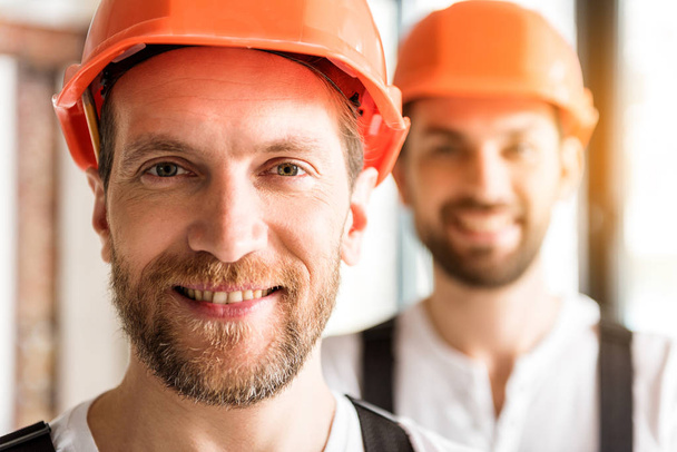 Constructores sonrientes alegres en cascos naranjas
 - Foto, Imagen