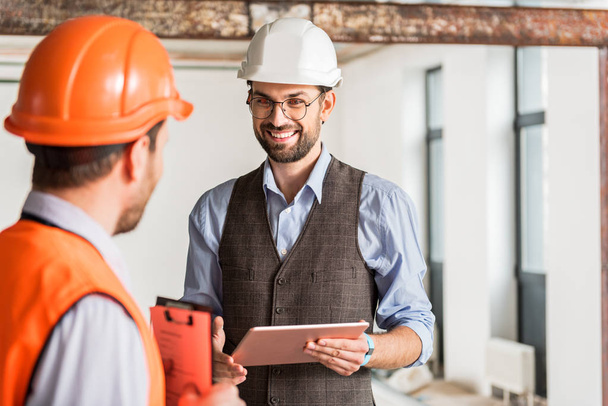 Hilarious smiling foreman talking to coworker - Photo, Image