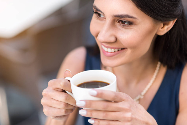 Beaming girl drinking cup of coffee - Photo, Image