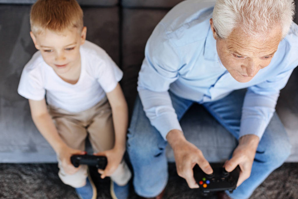 Diligent kid and his grandpa focused on a game - Foto, Imagen
