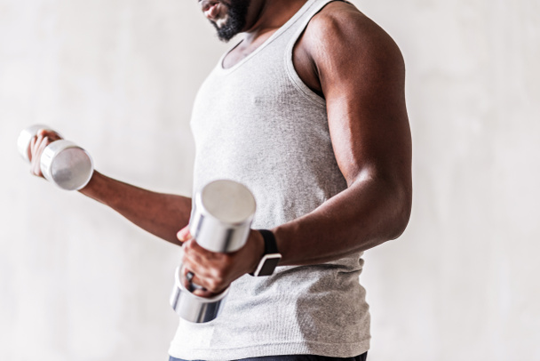 Serious well-build african athlete with beard performing workout with hand weights - 写真・画像