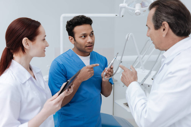 Foto de perfil del dentista que señala las herramientas para el estomatólogo
 - Foto, Imagen