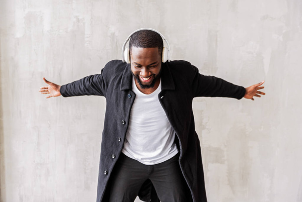 Jolly handsome african man with beard enjoying his beloved songs via earphones - Фото, зображення