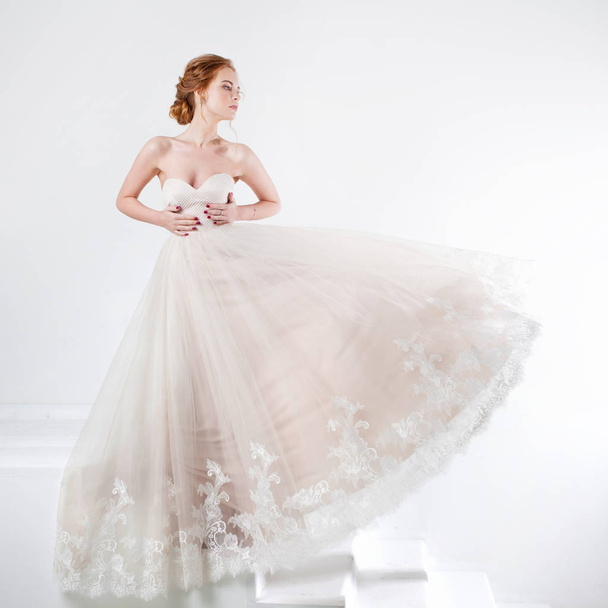 Portrait of a beautiful girl in a wedding dress. Bride in luxurious dress on a white background - Zdjęcie, obraz