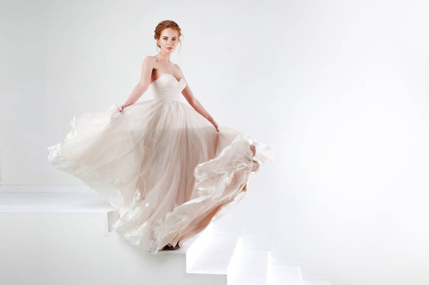 Portrait of a beautiful girl in a wedding dress. Bride in luxurious dress dancing and swinging hem skirt - Photo, image