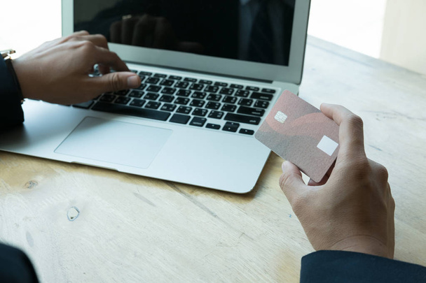 férfi gazdaság egy hitelkártya, és használata a laptop számítógép online  - Fotó, kép