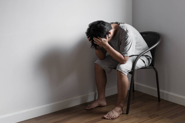 Depressiver junger Mann, der allein in der Ecke sitzt, Traurigkeit, Depressionen und Lebensprobleme - Foto, Bild