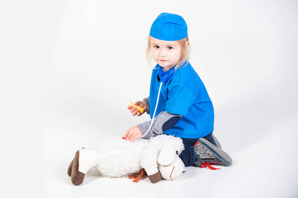 arts kind in uniforme spelen dierenarts met dier speelgoed - Foto, afbeelding