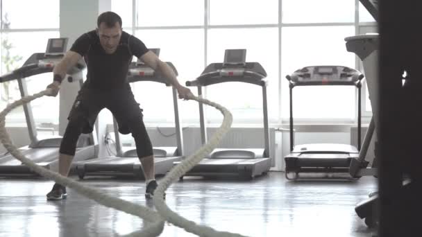 Movimento lento do homem com corda de batalha no ginásio de fitness de treinamento funcional
 - Filmagem, Vídeo