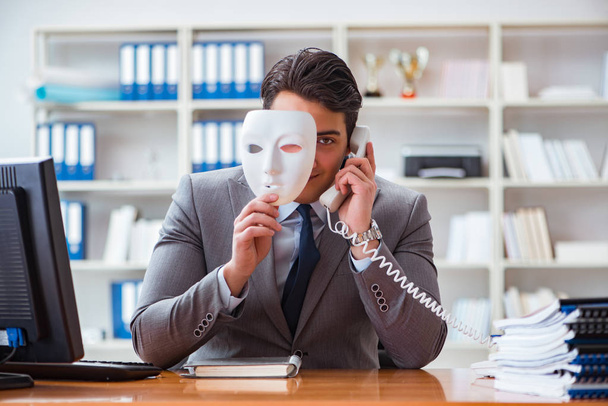 Бизнесмен в маске в офисе концепция лицемерия - Фото, изображение
