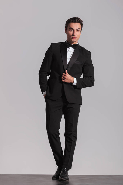 elegant man closing his tuxedo and looks to side - Foto, afbeelding