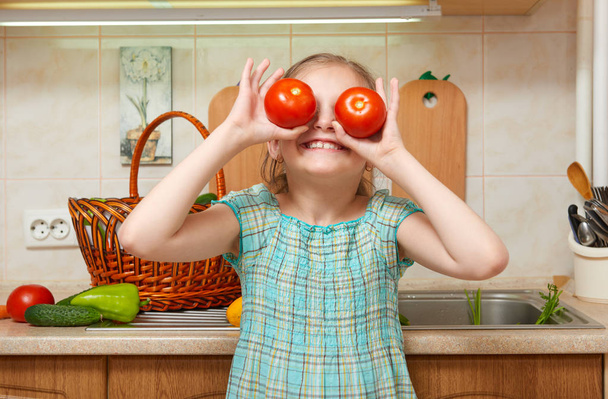 child girl with tomatoes, vegetables and fresh fruits in kitchen interior, healthy food concept - Fotoğraf, Görsel