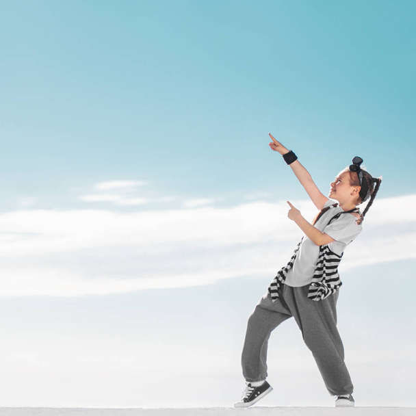 Fashion child pointing on copy space over sky background. Happy kid. - Foto, Imagen