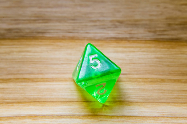 Un verde translúcido de ocho lados jugando dados en un backgro de madera
 - Foto, Imagen