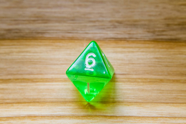 Egy áttetsző zöld nyolc oldalas játék kocka, a fából készült backgro - Fotó, kép