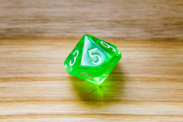 Un verde translúcido de diez lados jugando dados en un fondo de madera
 - Foto, Imagen