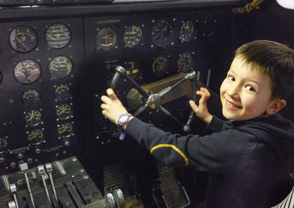 Νεαρό αγόρι χαμογελά, τιμόνι στο πιλοτήριο - Φωτογραφία, εικόνα