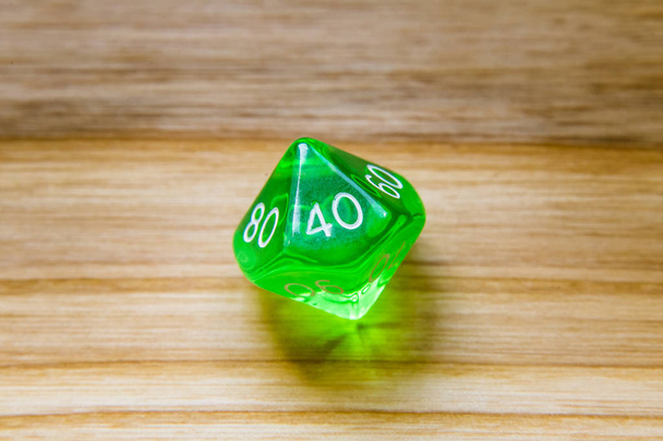 Полупрозрачный зеленый с десятью сторонами играя в кости на деревянной спинке
 - Фото, изображение