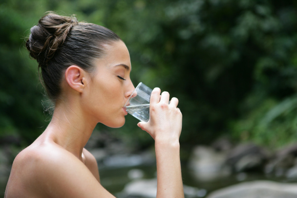 Morena bebiendo un vaso de agua al aire libre
 - Foto, imagen