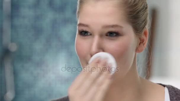 Young caucasian woman removes make up with a cotton pad - Felvétel, videó