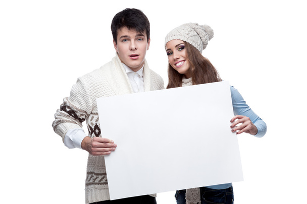 Joven sonriente pareja de invierno sosteniendo gran signo
 - Foto, imagen
