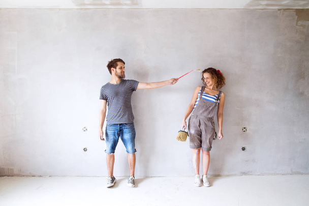Young couple in love painting walls in their new home. - 写真・画像