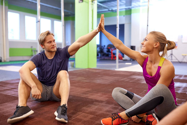happy couple making high five in gym - Фото, зображення