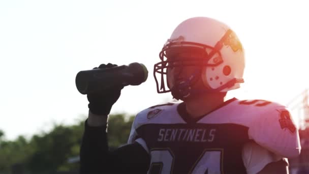 Un homme en costume de football au coucher du soleil boit de l'eau au ralenti
 - Séquence, vidéo