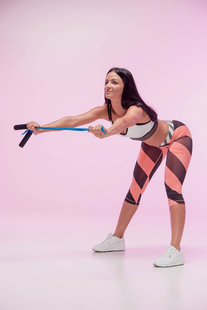 The woman training against pink studio with jump rope - Φωτογραφία, εικόνα