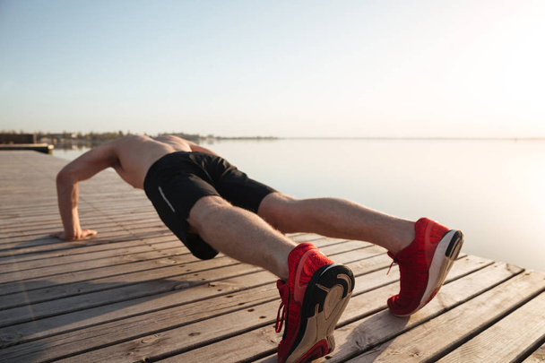 Portrait of a healthy young man doing push ups - Фото, изображение