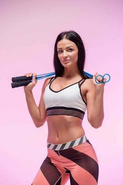 The woman training against pink studio with jump rope - Foto, immagini