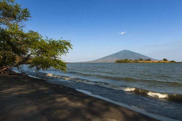 Пляж на острове Ометепе в озере Никарагуа, с вулканом на заднем плане, в Никарагуа
 - Фото, изображение