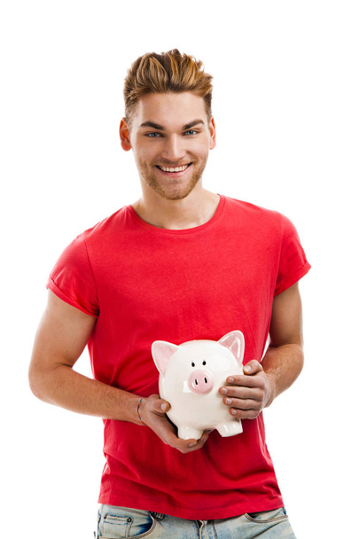 Handsome young holding a piggy bank - Photo, image