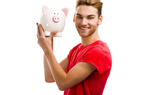 Handsome young holding a piggy bank - Foto, Imagen