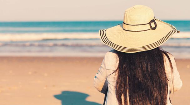 Woman in a hat sitting on the beach - Фото, изображение