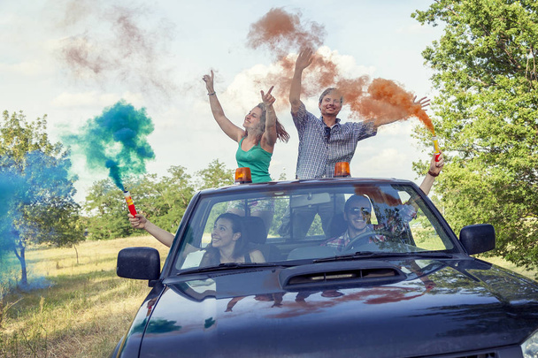 Group of young guys have fun with colored smoke trails - Фото, зображення