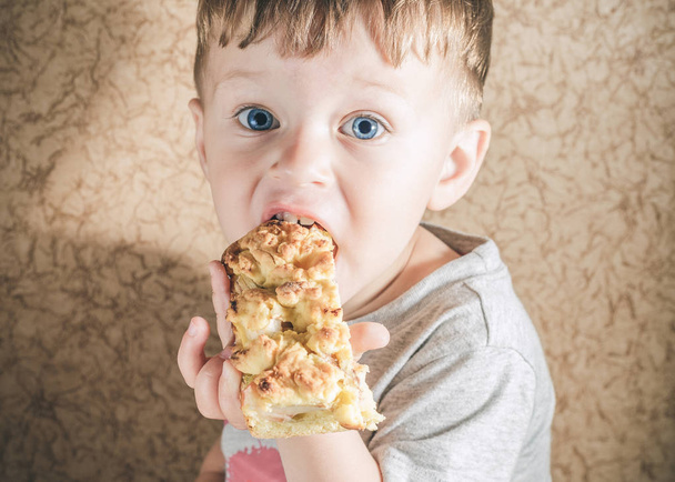 Хлопчик Тоддлер їсть великий шматок пирога
 - Фото, зображення