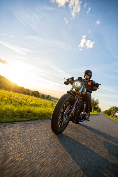 Dark motorbiker riding high power motorbike in sunset - Fotó, kép