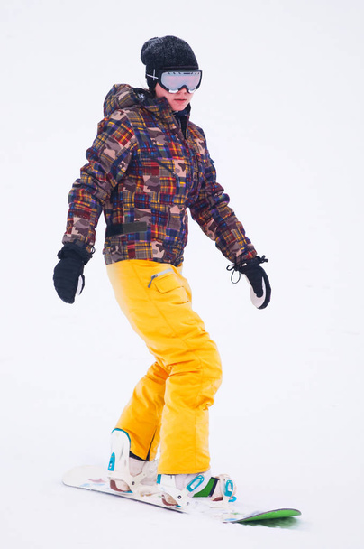 Young girl snowboarder in yellow pants on the board - Foto, afbeelding