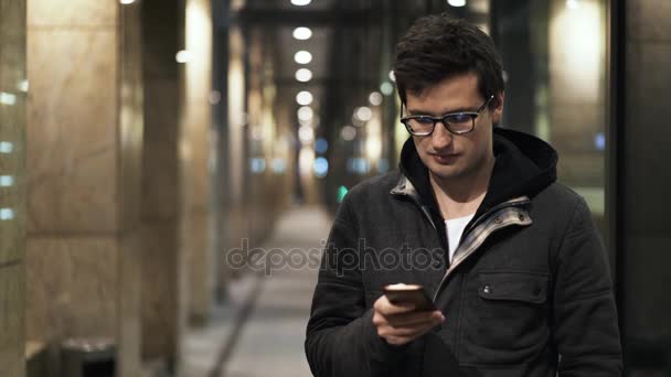 junger Mann, der abends auf der Straße SMS schreibt - Filmmaterial, Video